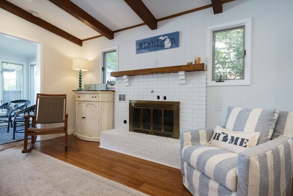 A living room with a fireplace, a striped sofa, a wooden chair, and a sign that says "Michigan".