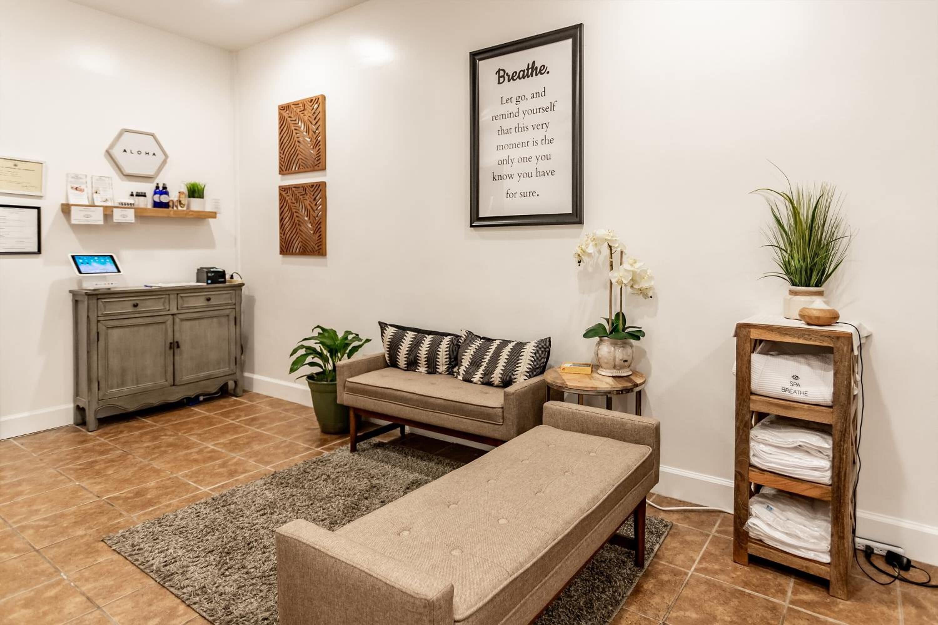Een moderne woonkamer met een bank, een zitbank en een wandplank met handdoeken.