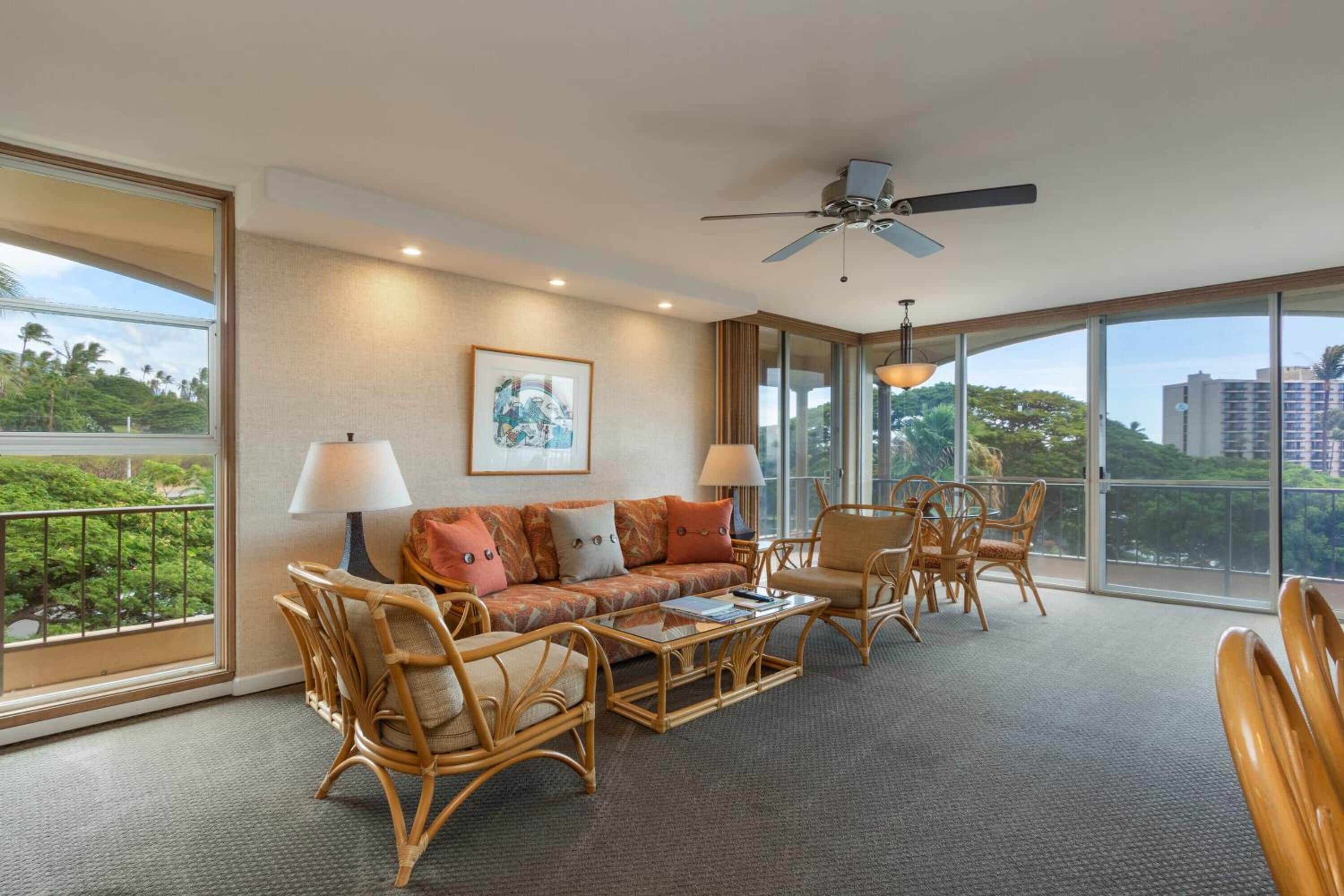 A spacious room with a large window, a ceiling fan, a sofa set, and a dining table.