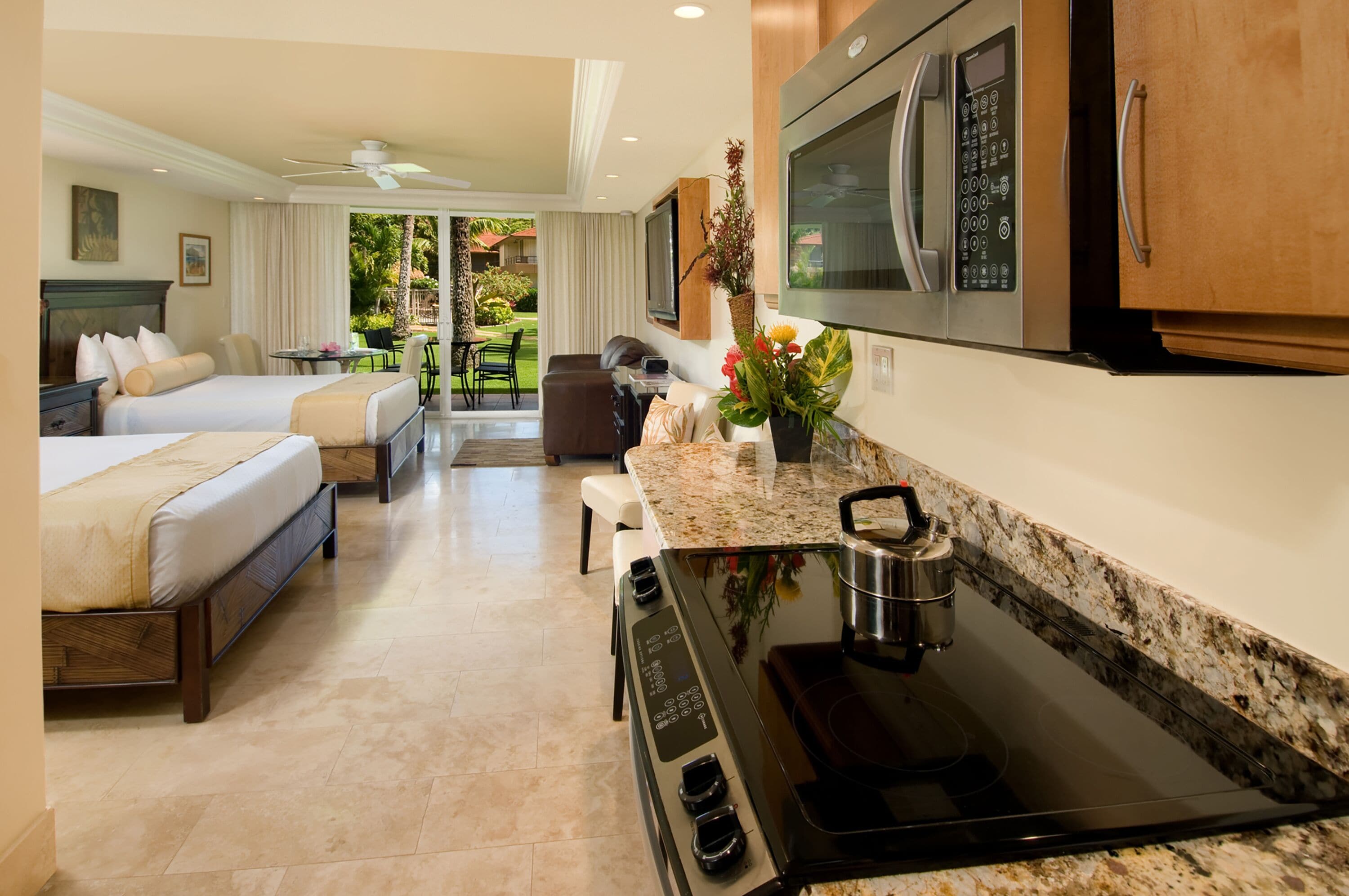 Habitación de hotel con kitchenette, zona de comedor y balcón con vista al jardín.
