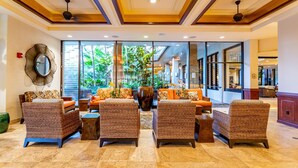 A lobby with wicker furniture, a large mirror, and a view of the outdoors.