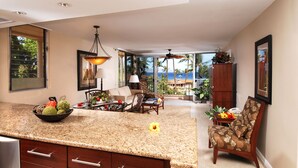 A spacious kitchen with granite countertops, wooden cabinets, and a dining area with a view of the ocean.