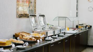 Disposição de buffet com diversos alimentos e um espelho decorativo na parede.