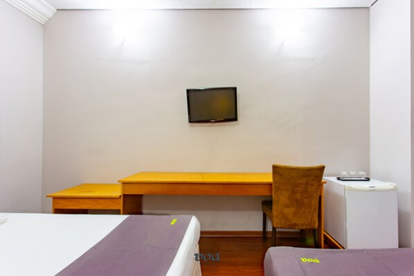 A room with a bed, a desk, a chair, a television, and a small table.