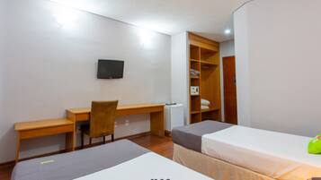 A hotel room with a bed, a desk, a chair, a TV, and a wardrobe.