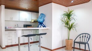Una cucina con mobili bianchi, un distributore d'acqua blu e due sgabelli da bar.