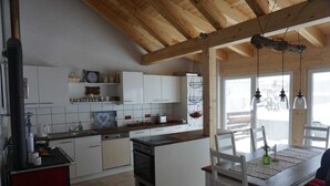 A modern kitchen with white cabinets, a central island, and a dining area with a wooden table and chairs. - "Vacation cottage Plättig" (Bühlertal)