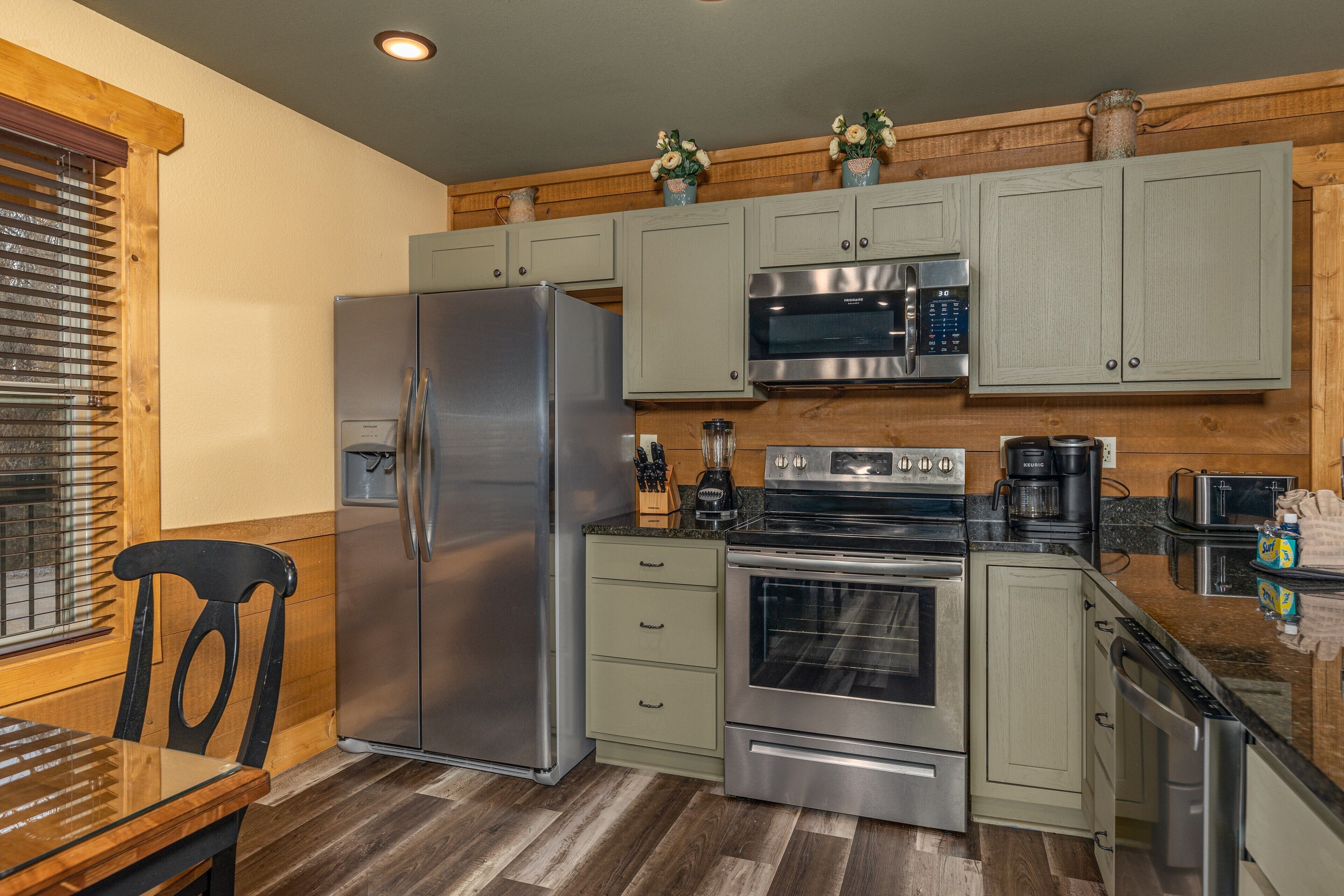 A modern kitchen with stainless steel appliances, light wood cabinetry, and a dining area with a wooden table and chairs.