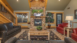 A cozy living room with a stone fireplace, leather sofas, and a large TV. - Beautiful Vista (Pigeon Forge)