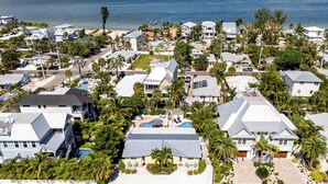 Et kystnært boligområde med huse, en strand og en swimmingpool.
