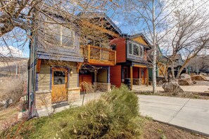A two-story house with a balcony, a garage, and a front yard with shrubs. - KBM Resorts | Private Home | Split AC in living room | Walk to Town and to Ski Access, Hot Tub and Fire Pit! PNF-860 (Park City)