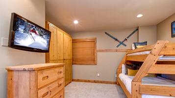 A cozy room with wooden bunk beds, a TV mounted on the wall, and a ski-themed decoration.