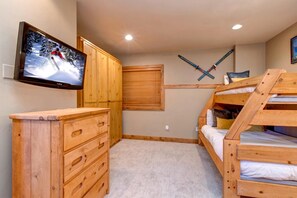 Una habitación acogedora con literas de madera, un televisor montado en la pared y decoración con temática de esquí.