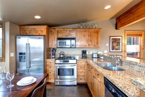 A modern kitchen with wooden cabinets, stainless steel appliances, granite countertops, and a dishwasher.