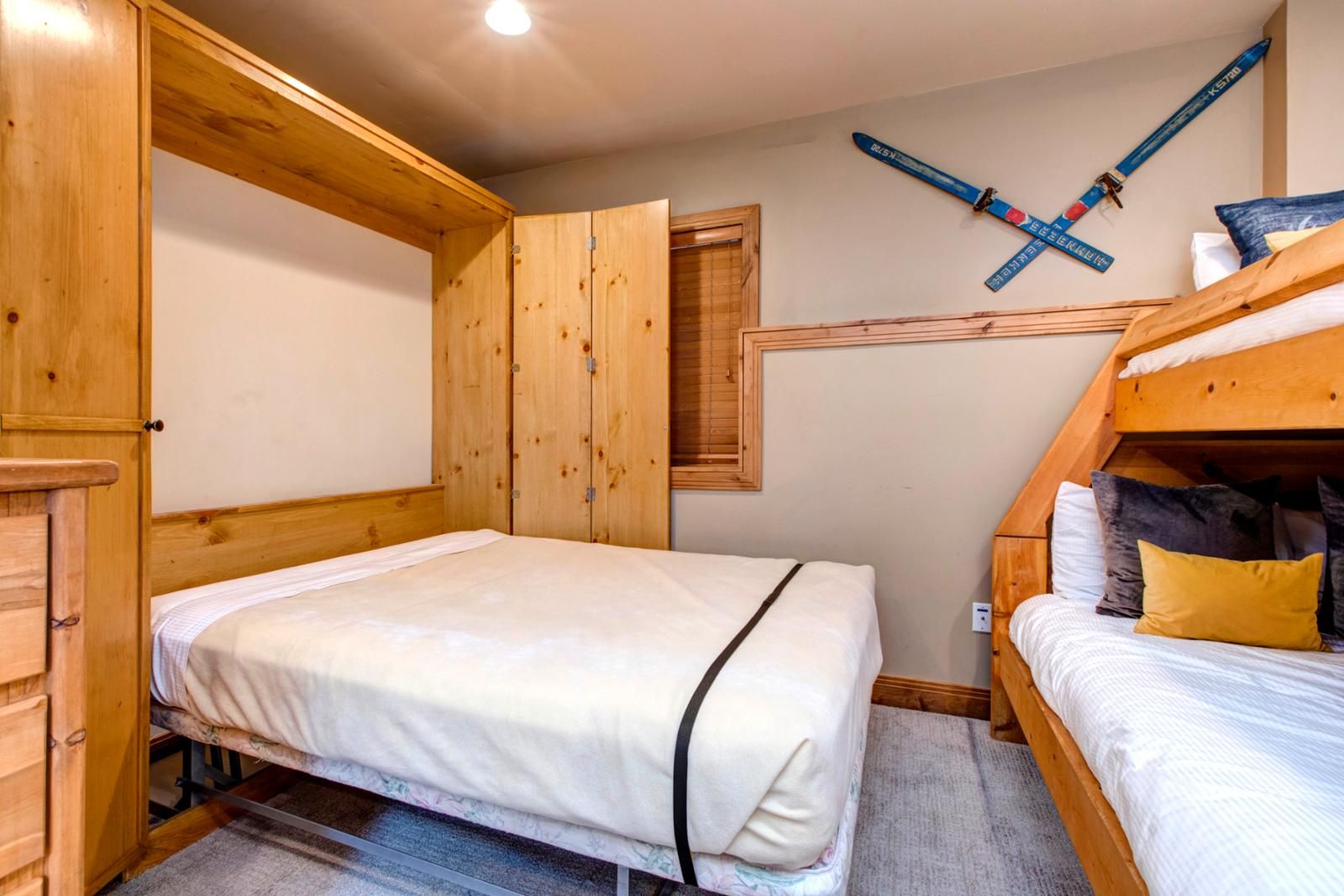 Quarto com uma cama de solteiro, uma cama de casal e paredes de madeira, além de um suporte para esquis.