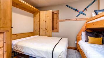 Quarto com uma cama de solteiro, uma cama de casal e paredes de madeira, além de um suporte para esquis.