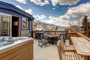 Un patio con jacuzzi, mobiliario exterior y vistas a las montañas.