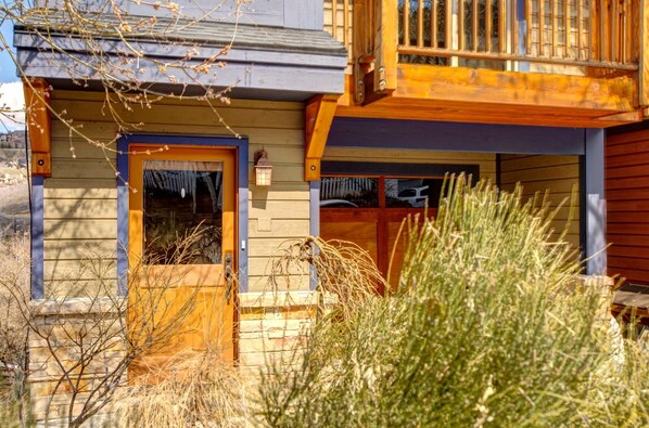 Une cabane en bois avec une porte d’entrée, un petit porche et une fenêtre.