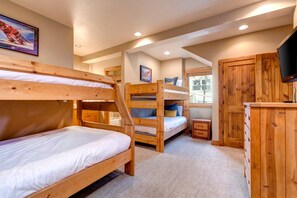 Habitación con literas, un aparador de madera y un televisor.