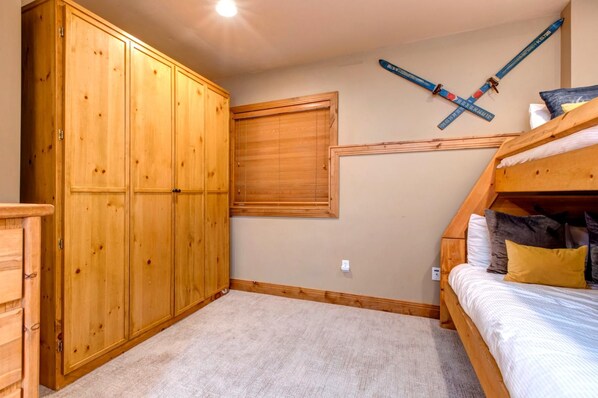 Un dormitorio con literas, armario de madera y decoración temática de esquí.