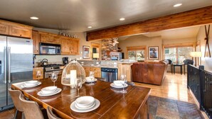 A spacious kitchen with wooden cabinets, a stainless steel refrigerator, and a dining area with a wooden table set for four. - KBM Resorts | Private Home | Split AC in living room | Walk to Town and to Ski Access, Hot Tub and Fire Pit! PNF-860 (Park City)