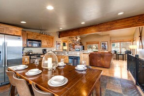 A spacious kitchen with wooden cabinets, a stainless steel refrigerator, and a dining area with a wooden table set for four.