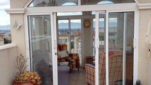 A covered patio with a sliding glass door leading to an interior space with two sofas and a small table. - Fully licensed 2 bedroom 2 bathroom detached villa with private pool .  (Benimar rojales)