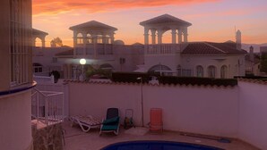 A rooftop pool area with lounge chairs and a view of a white building with arches during sunset. - Fully licensed 2 bedroom 2 bathroom detached villa with private pool .  (Benimar rojales)