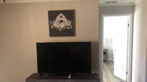 Un salon avec un grand téléviseur à écran plat posé sur un meuble de télévision en bois foncé.