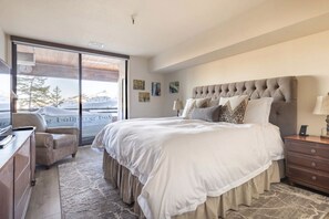 A bedroom with a large bed, a desk, a chair, and a sliding glass door leading to a snowy outdoor area.