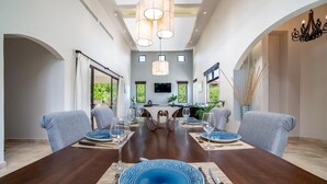 A dining area with a long table set for six, featuring blue patterned plates and a central chandelier. - Casa Bonita Beach (Tamarindo)
