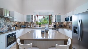 A modern kitchen with a central island, white cabinetry, and patterned backsplash. - Casa Bonita Beach (Tamarindo)