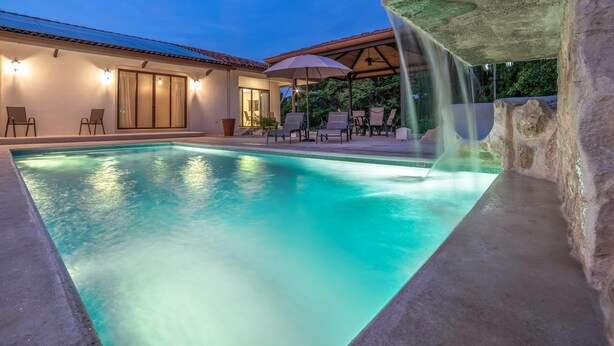 A swimming pool with a waterfall feature, surrounded by lounge chairs and umbrellas. - Casa Bonita Beach (Tamarindo)