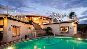 A two-story house with a swimming pool, stairs leading to the upper level, and a balcony.