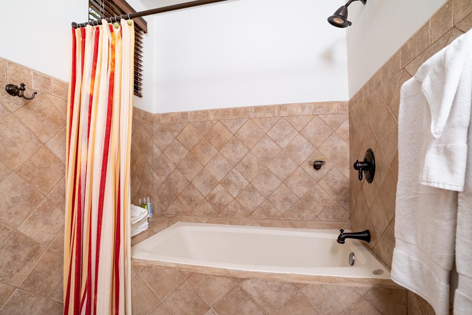 Un baño con bañera, cortina de ducha y toallero.