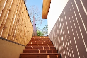 A wooden staircase with bamboo walls on either side, leading to a higher level.