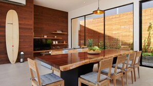 Un comedor moderno con una mesa de madera, sillas y un gran ventanal con persianas.