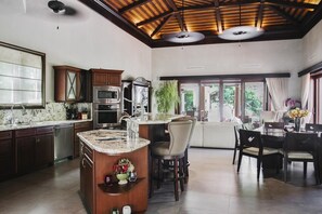 A spacious kitchen with modern appliances, a large island, and a dining area with a view of the outdoors.