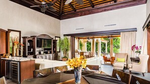 Un vaste espace de vie comprenant une grande table à manger, une cuisine équipée d’un téléviseur à écran plat et une terrasse avec des meubles d’extérieur.