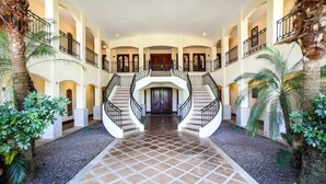 A spacious interior with a central staircase, multiple balconies, and tropical plants. - Villa Tranquila (Tamarindo)