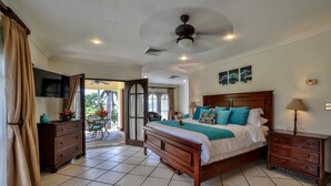 A bedroom with a bed, bedside tables, a TV, and a balcony with a table and chairs. - Villa Tranquila (Tamarindo)