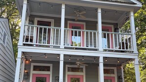 Une maison à deux étages avec un porche, une porte d’entrée dotée d’un cadre rose et une boîte aux lettres.