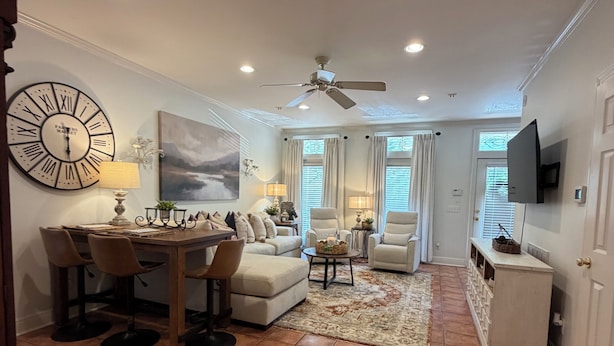Un salon spacieux comprenant un coin repas, un ventilateur de plafond et une grande horloge murale.