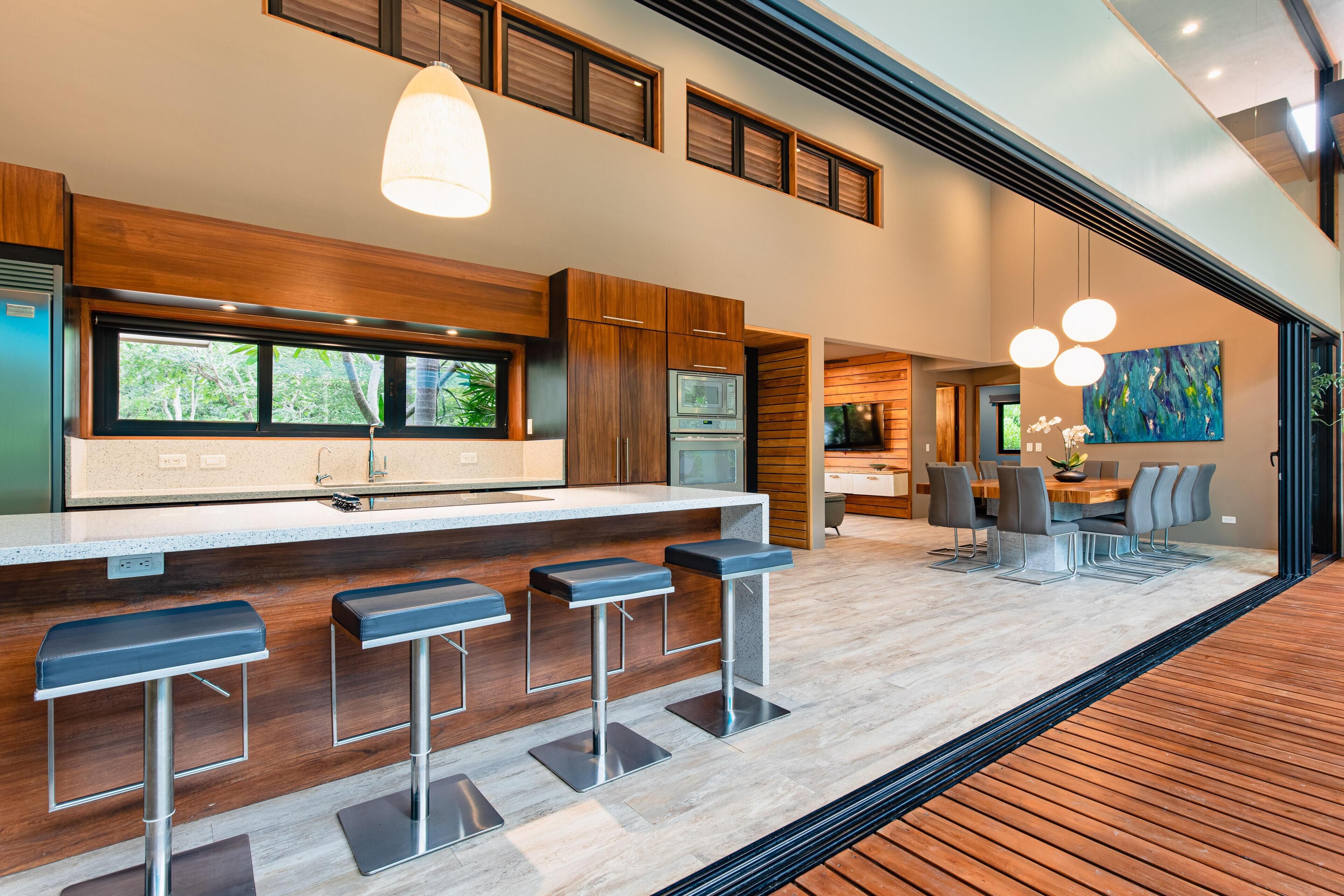 Cozinha moderna com uma ilha grande, banquetas e um espaço de jantar com mesa e cadeiras.