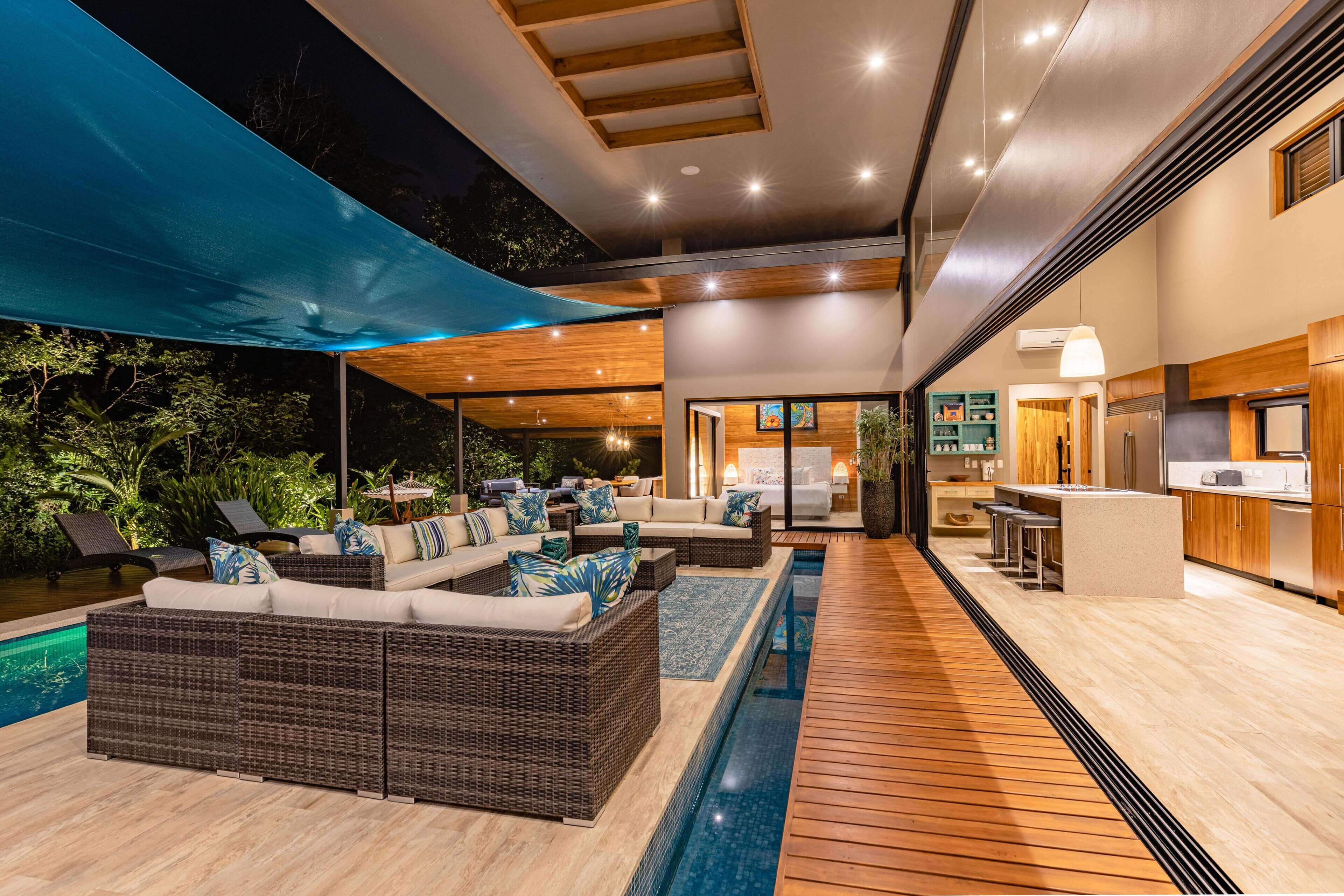 Uma área externa moderna com piscina, móveis de vime e cozinha.