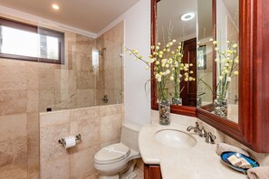 A modern bathroom with a glass-enclosed shower, a toilet, a sink with a vanity, and decorative plants.