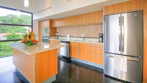 A modern kitchen with wooden cabinets, a stainless steel refrigerator, and a granite countertop.