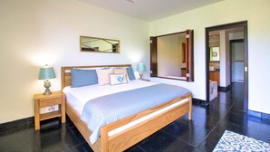 A bedroom with a large bed, two bedside tables with lamps, a mirror, and a view of the bathroom.