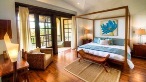 A spacious bedroom with a four-poster bed, a large window, and a ceiling fan. - Villa Mansita (Tamarindo)