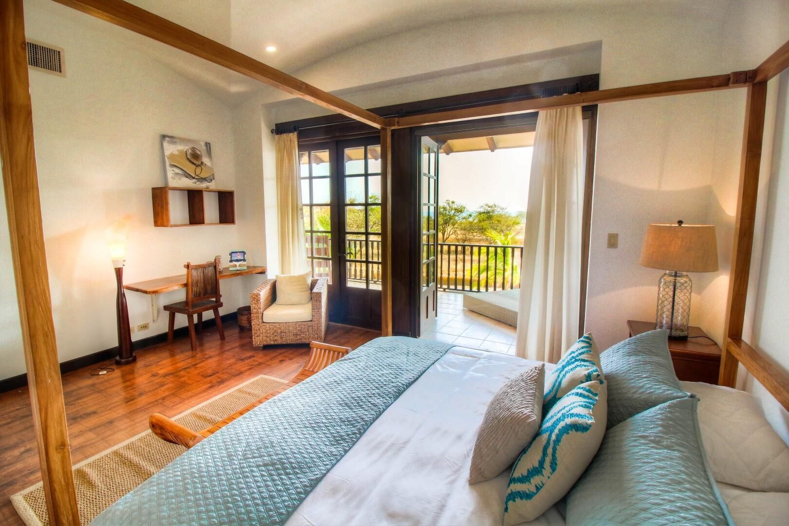 Een slaapkamer met een groot bed, een bureau, een stoel en uitzicht op de omgeving.